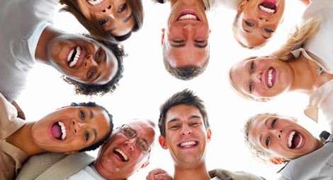 A group of different aged and gendered people all looking down and smiling